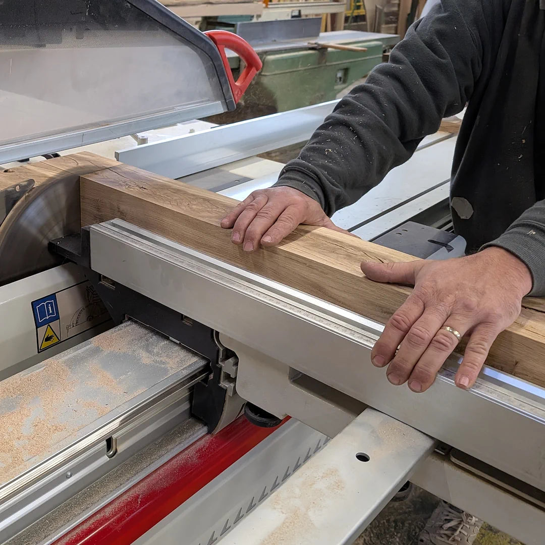 Artisan débitant une poutre chêne